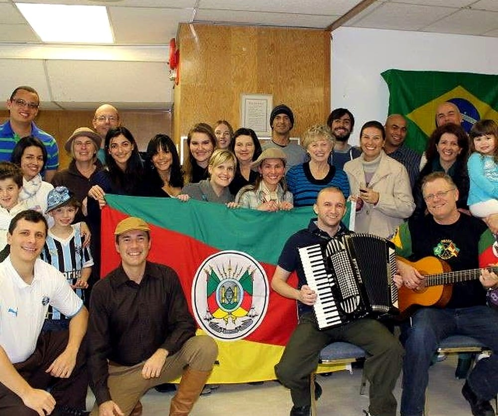 Grupo do CTG Gaúchos da Aurora no Canadá com bandeira do Rio Grande do Sul