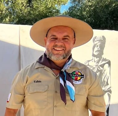 Homem sorridente de chapéu e uniforme de escoteiro, com lenço no pescoço