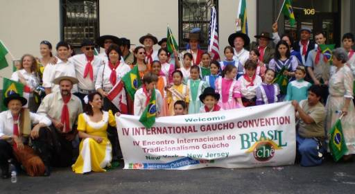 Grupo de pessoas em trajes tradicionais segurando faixa do IV Encontro Internacional do Tradicionalismo Gaúcho no Brasil, em New Jersey