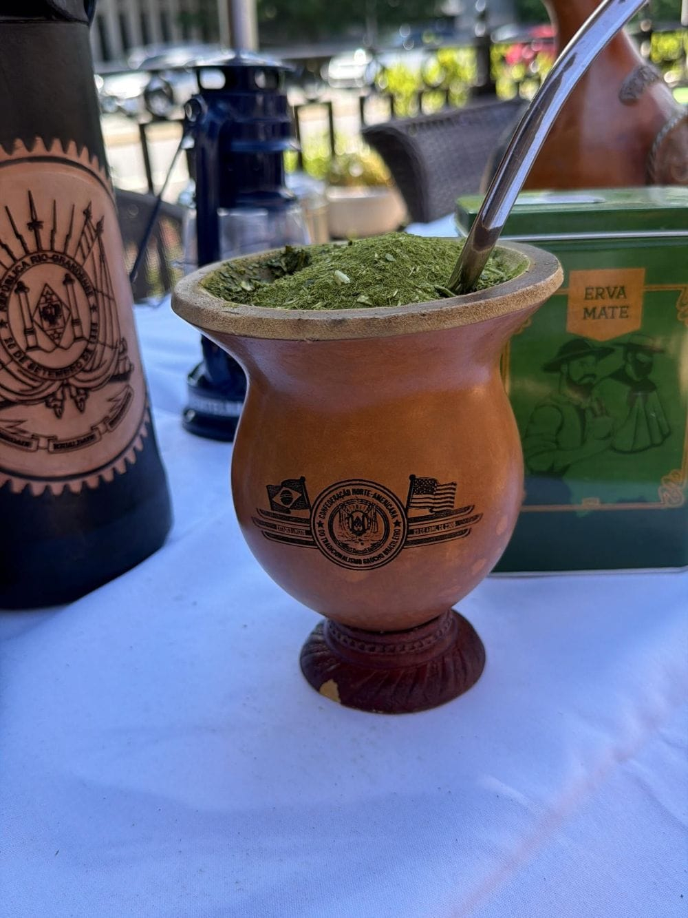 Cuia de chimarrão com erva-mate e bomba sobre a mesa, ao ar livre