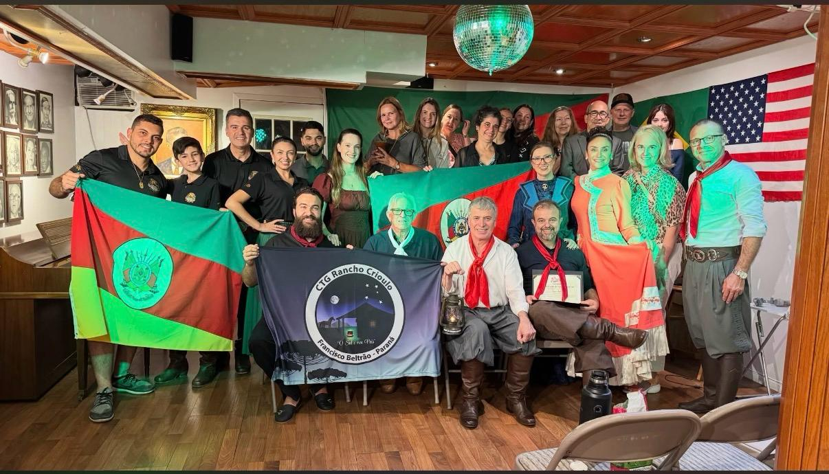 Grupo reunido com bandeiras do Rio Grande do Sul e do CTG Rancho Crioulo no evento de 18 de setembro de 2026.