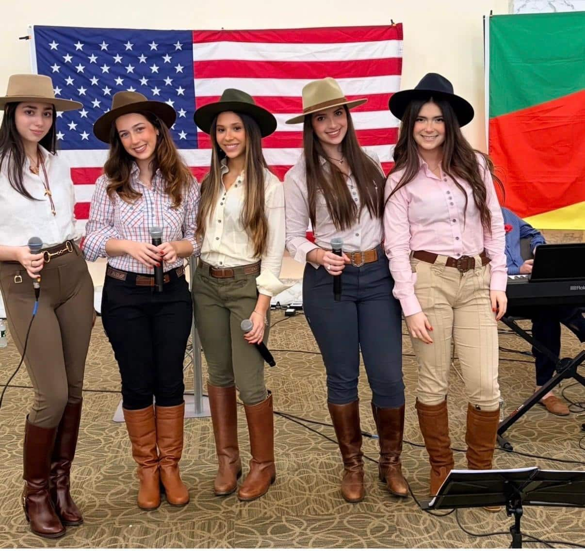 As Pampeanas com chapéus e microfones, diante das bandeiras dos Estados Unidos e do Rio Grande do Sul.