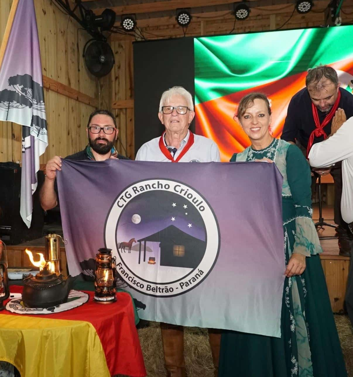 Renato Berman, Sr. Rui Machado e Marciane Laskoski com a bandeira do CTG Rancho Crioulo.